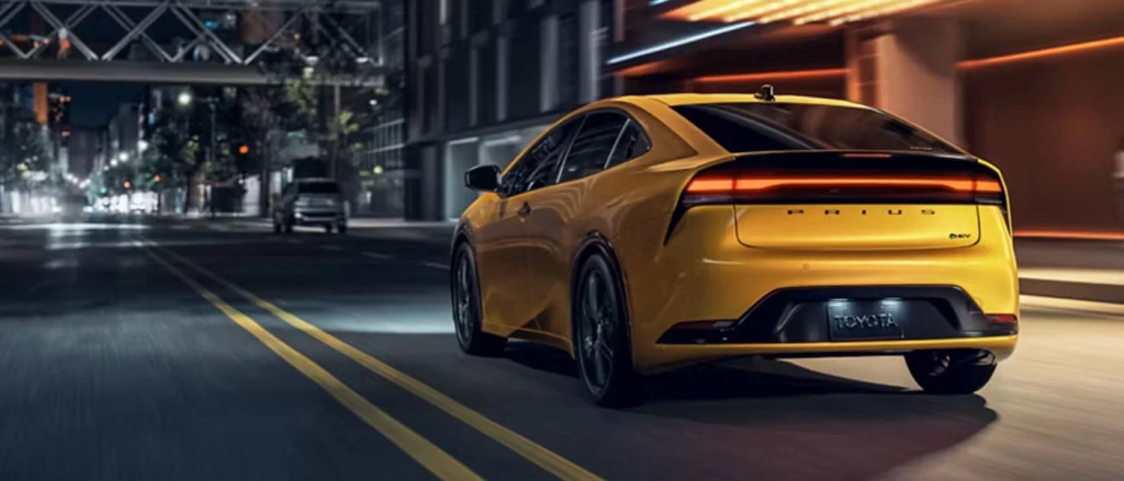 The 2026 Toyota Prius from behind driving on a city road